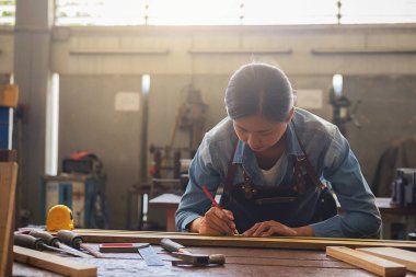 Marangoz marangozluk dükkanda ahşap işleme makineleri üzerinde çalışıyor. kadın bir marangozluk dükkanında çalışıyor.
