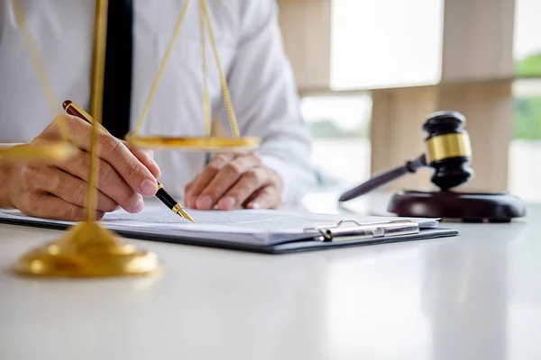 Justice and Law concept. Legal counsel presents to the client a signed contract with gavel and legal law or legal having team meeting at law firm in background