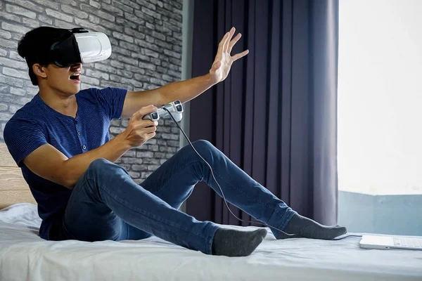 Young man in bedroom playing a virtual reality video game