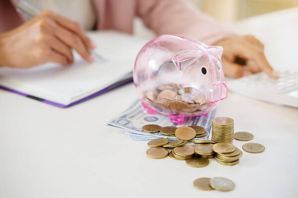 Business people sheltering coins and piggy bank at desk. saving concept