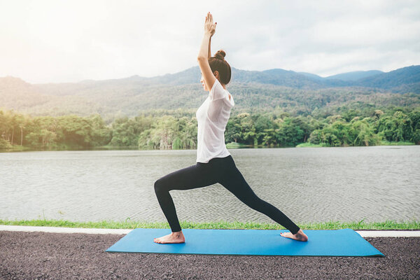 Yoga concept. Young woman meditates while practicing yoga in park. Calmness and relax, female happiness. blurred garden on the background