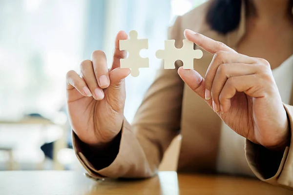 Business woman hands connecting jigsaw puzzle. Business solutions, success and strategy concept. Close up photo with selective focus.