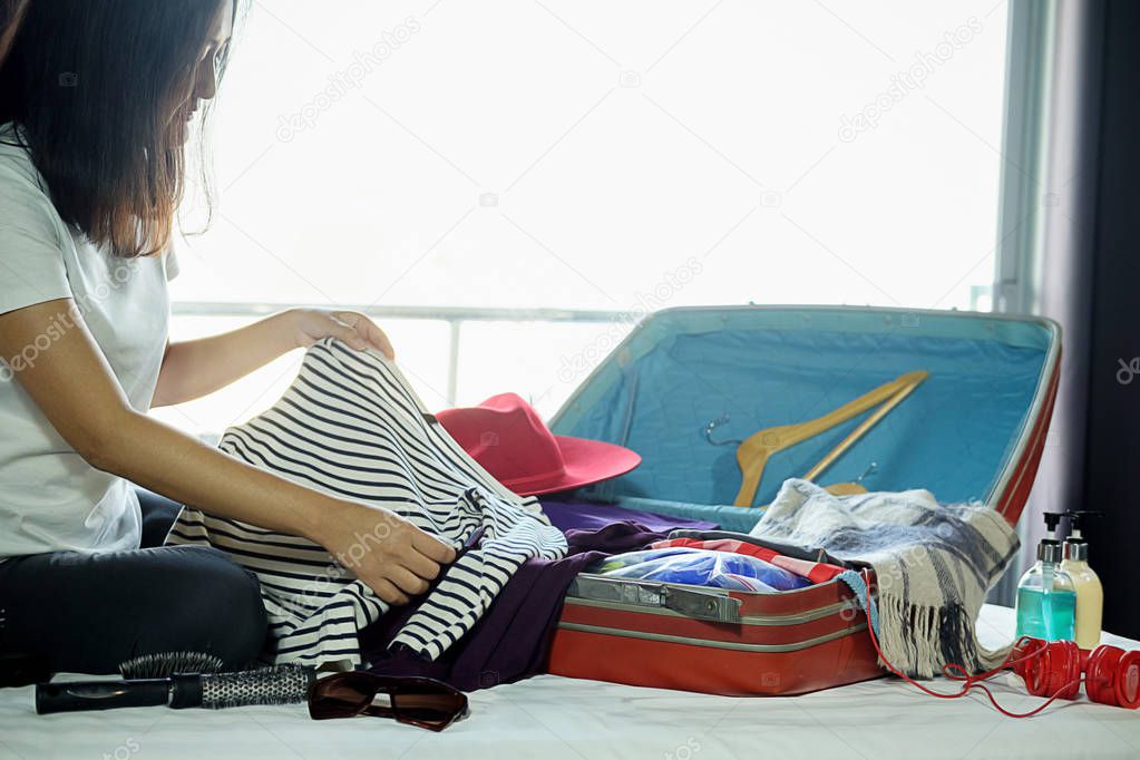 People packed suitcase with travel accessories on bed. Vacation concept