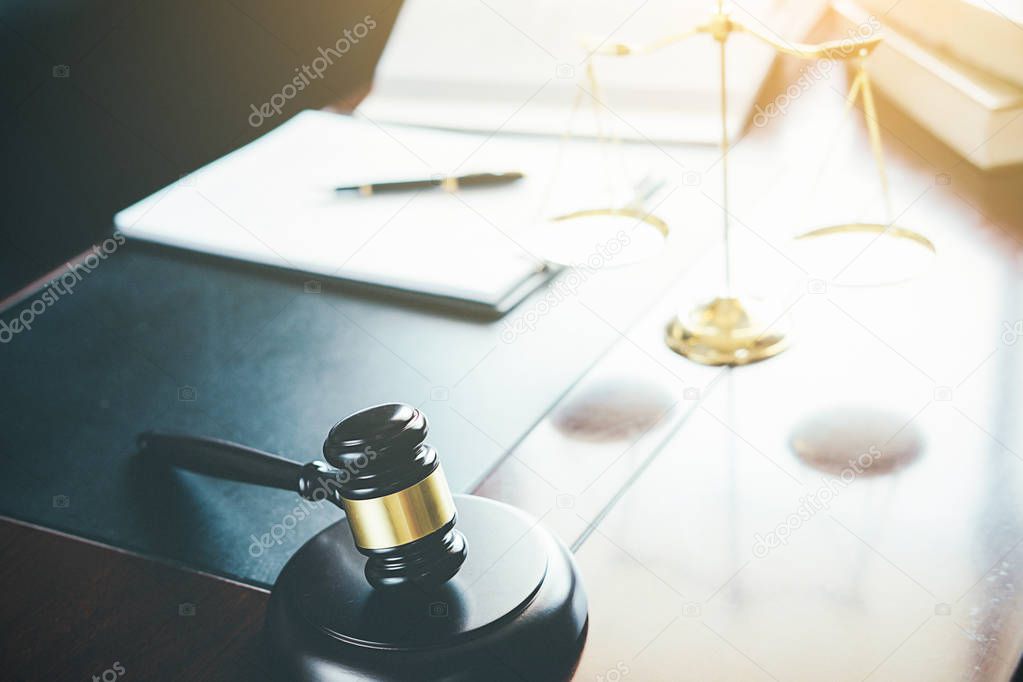 Justice and Law concept. Legal counsel presents to the client a signed contract with gavel and legal law or legal having team meeting at law firm in background