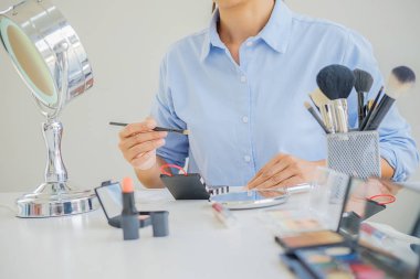 Kadın dijital kamera kullanarak kozmetik üzerine blogu için video çekiyor. Genç bayan blogcu elinde kozmetik malzemelerle kamera ekranında.