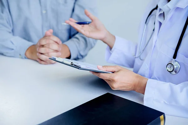 Patient hört aufmerksam zu, wie ein männlicher Arzt den Patienten erklärt — Stockfoto