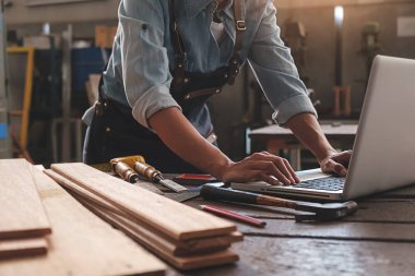 Marangoz, marangozluk işindeki ahşap masada ekipmanla çalışıyor.
