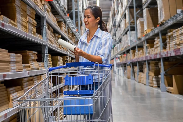 Asian woman with market trolley at furniture store