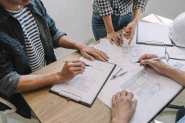 Bir ofiste bir tablet bilgisayardaki bilgileri denetlenirken bir plan mühendisleri tartışmak.