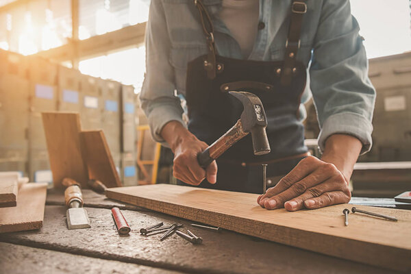 Carpenter working with equipment on wooden table in carpentry sh