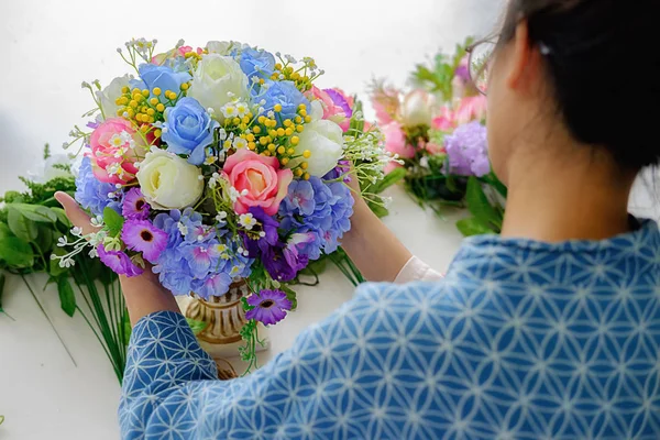 Manos de mujer haciendo composición de flores en el taller de floristería. Hazlo. — Foto de Stock