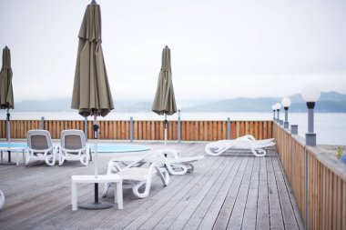 Ahşap güverte plaj deniz okyanus resort Paz aylâk şemsiye otel havuzu gökyüzü güneş doğuyor. Deniz kenarında Ahşap Teras günbatımı akşamı sakin ol.