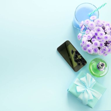 Surrealiam kompozisyon düz yatıyordu hediye bir kadın için. Modern gadget cep telefonu cam kokteyl parfüm buket. Tatil sürpriz hediye kutusu için hazırlanıyor. Üstten görünüm mavi arka plan
