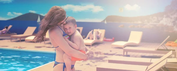 Banner Young mom holding a baby relaxing by the pool shines the bright sun. Summer season family vacation travel