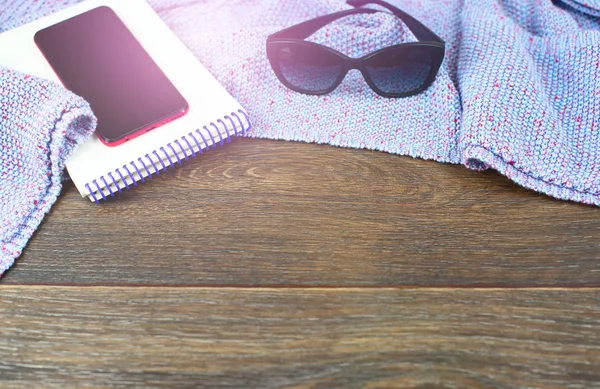 Empty space on your desktop mobile phone gadget Notepad sunglasses. Old natural wooden shabby background knitted blanket plaid purple color sunlight glare glow