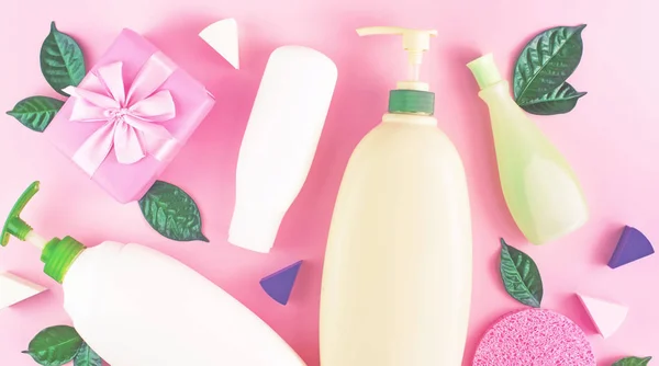 Banner Cosmetic packaging plastic bottle shampoo cream shower gel milk green leaves sponge box gift bow. Natural organic product skin and hair care shopping. Top view pink flat lay background. Selective focus