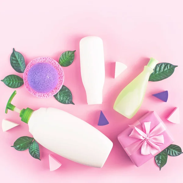 Cosmetic packaging plastic bottle shampoo cream shower gel milk green leaves sponge box gift bow. Natural organic product skin and hair care shopping. Top view pink flat lay background. Selective focus
