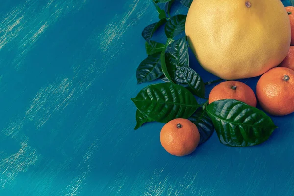 Parlak mavi arka plan üst üzerinde yeşil yaprakları ile olgun mandalina düz yatıyordu kopya alanı göster