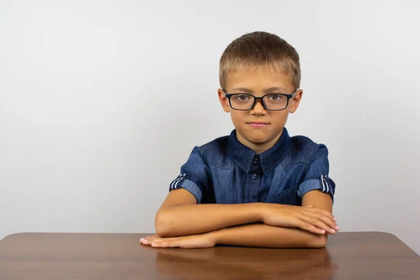 Garçon étudiant assis à une table sur un fond clair . — Photo