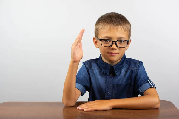 Junge Student sitzt an einem Tisch auf hellem Hintergrund. — Stockfoto