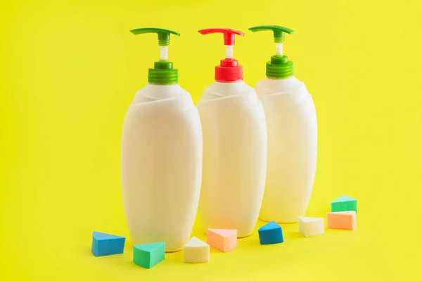 Tres botellas de plástico con dispensador sobre fondo amarillo . —  Fotos de Stock