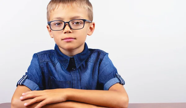 Banner Schoolboy in camicia blu seduto al tavolo. Ragazzo con gli occhiali su sfondo bianco Concetto torna a scuola — Foto Stock