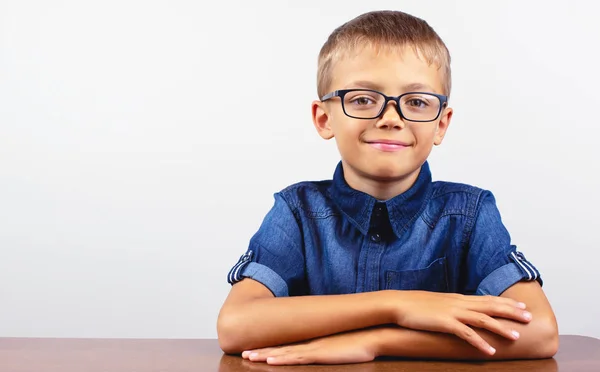 Banner Schoolboy in camicia blu seduto al tavolo. Ragazzo con gli occhiali su sfondo bianco Concetto torna a scuola — Foto Stock