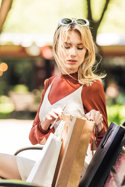 Bela Jovem Mulher Sentada Banco Olhando Para Saco Compras — Fotografia de Stock