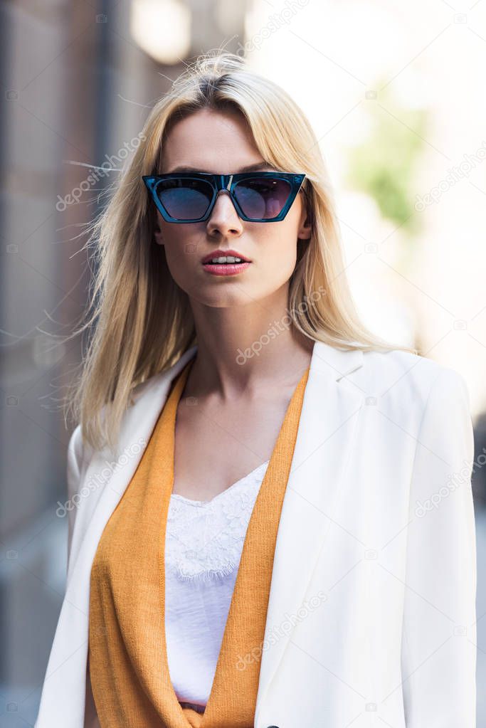 portrait of beautiful young blonde woman in sunglasses looking at camera