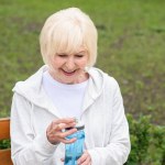 Lachende senior vrouw houdt van sport fles water
