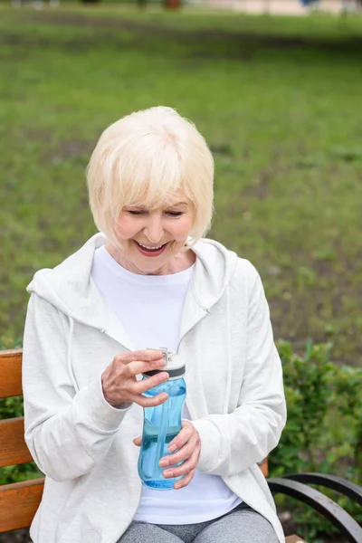 水のスポーツ ボトルを保持している年配の女性の笑顔  — 無料ストックフォト