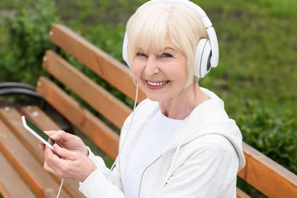 Χαρούμενη Ηλικιωμένη Γυναίκα Που Ακούει Μουσική Ακουστικά Και Smartphone — Φωτογραφία Αρχείου