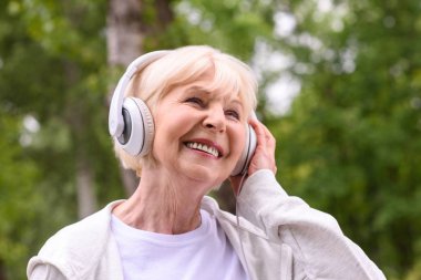 gülümseyen kıdemli sporcumuz Park kulaklık ile müzik dinleme