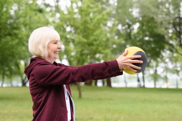老年妇女在公园锻炼与医学球 — 图库照片