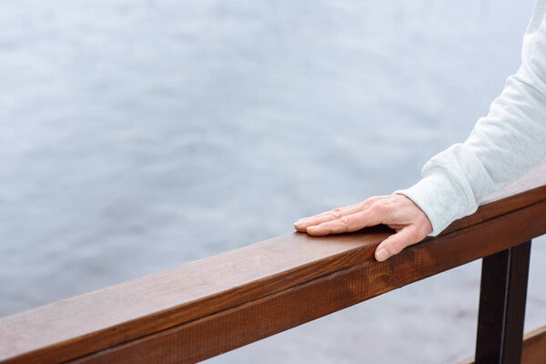 partial view of female hand on wooden railings
