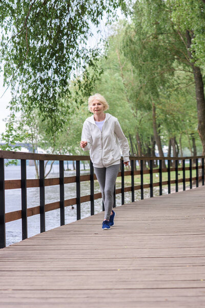senior sportswoman running on wooden path in park