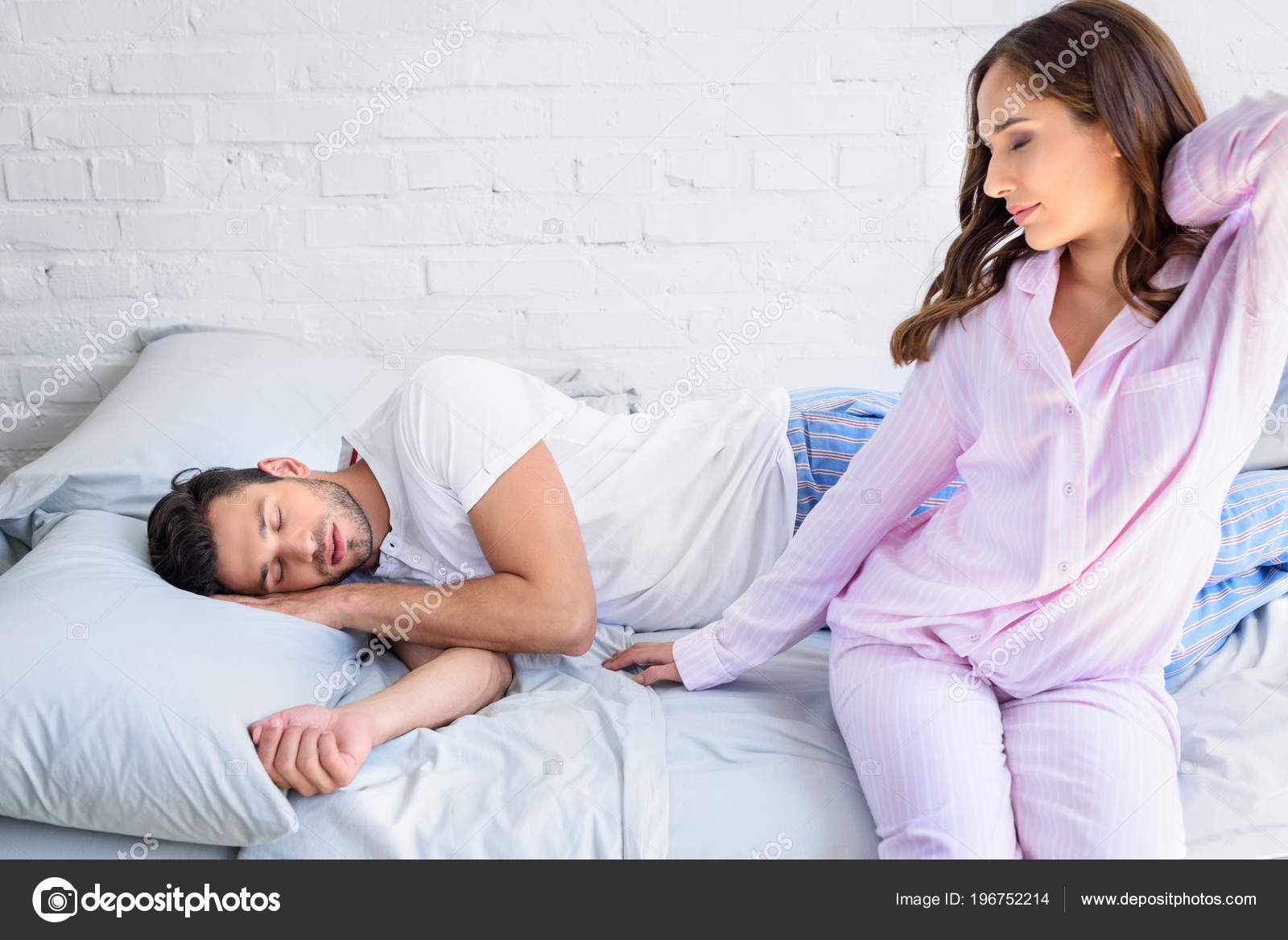 Hermosa Joven Mujer Pijama Sentado Cama Estiramiento Mientras Novio Durmiendo Foto de stock 196752214 IgorVetushko