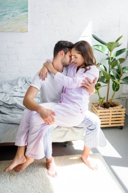 young tender woman sitting on knees of her boyfriend and hugging him on bed  clipart