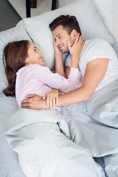 Jovem Casal Sorridente Abraçando Olhando Para Outro Enquanto Relaxa Cama — Fotografia de Stock