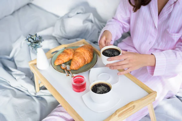 妇女在粉红色睡衣的裁剪视图在床上吃早饭 — 图库照片