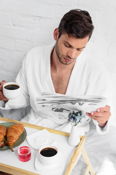 Young Handsome Man Bathrobe Reading Newspaper Breakfast Coffee Croissants — Free Stock Photo