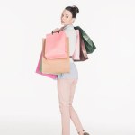 Side view of stylish woman with shopping bags looking at camera isolated on white