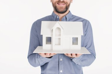 cropped shot of bearded man holding house model in hands isolated on white clipart