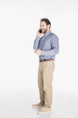 sakallı adam elinde beyaz izole Smartphone cep telefonu ile konuşurken kredi kartıyla yan görünüm