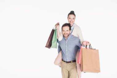 happy woman with shopping bags and husband piggybacking together isolated on white