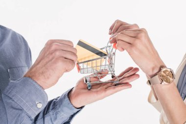 küçük alışveriş sepeti ve kredi kartı üzerinde beyaz izole elinde tutan bir çift atış kırpılmış