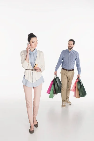 Woman Credit Card Talking Smartphone While Husband Carrying Shopping Bags — Free Stock Photo