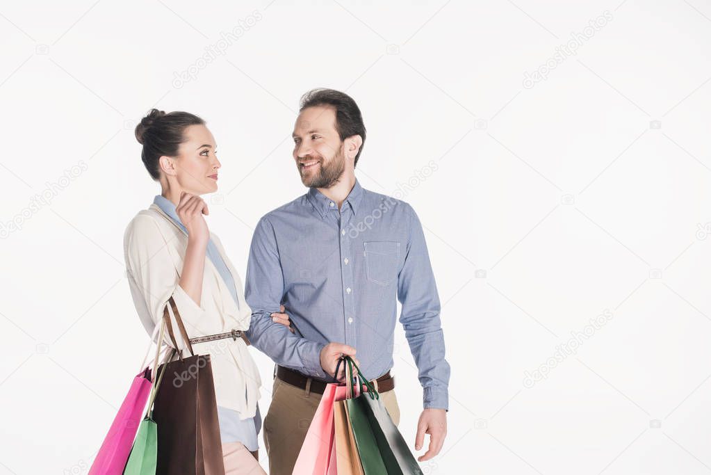 portrait of cheerful couple with shopping bags isolated on white