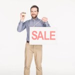 Homme souriant avec carte de vente et carte de crédit dans les mains isolées sur blanc