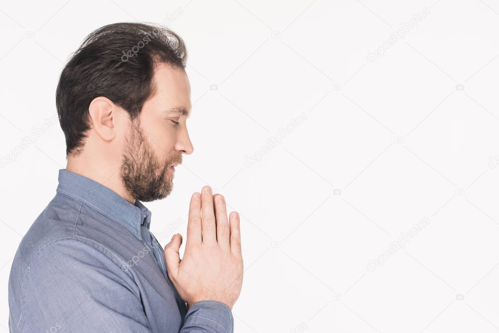 side view of bearded man in shirt praying isolated on white